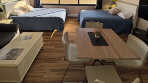 A room with two beds, a ceiling fan, a table with chairs, and a large window with a view. - Cozy Studio l Oceanfront l Pool l WiFi (Ocean City)