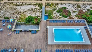 An aerial view of a hotel with a swimming pool, sun loungers, and a beach area. - Cozy Studio l Oceanfront l Pool l WiFi (Ocean City)