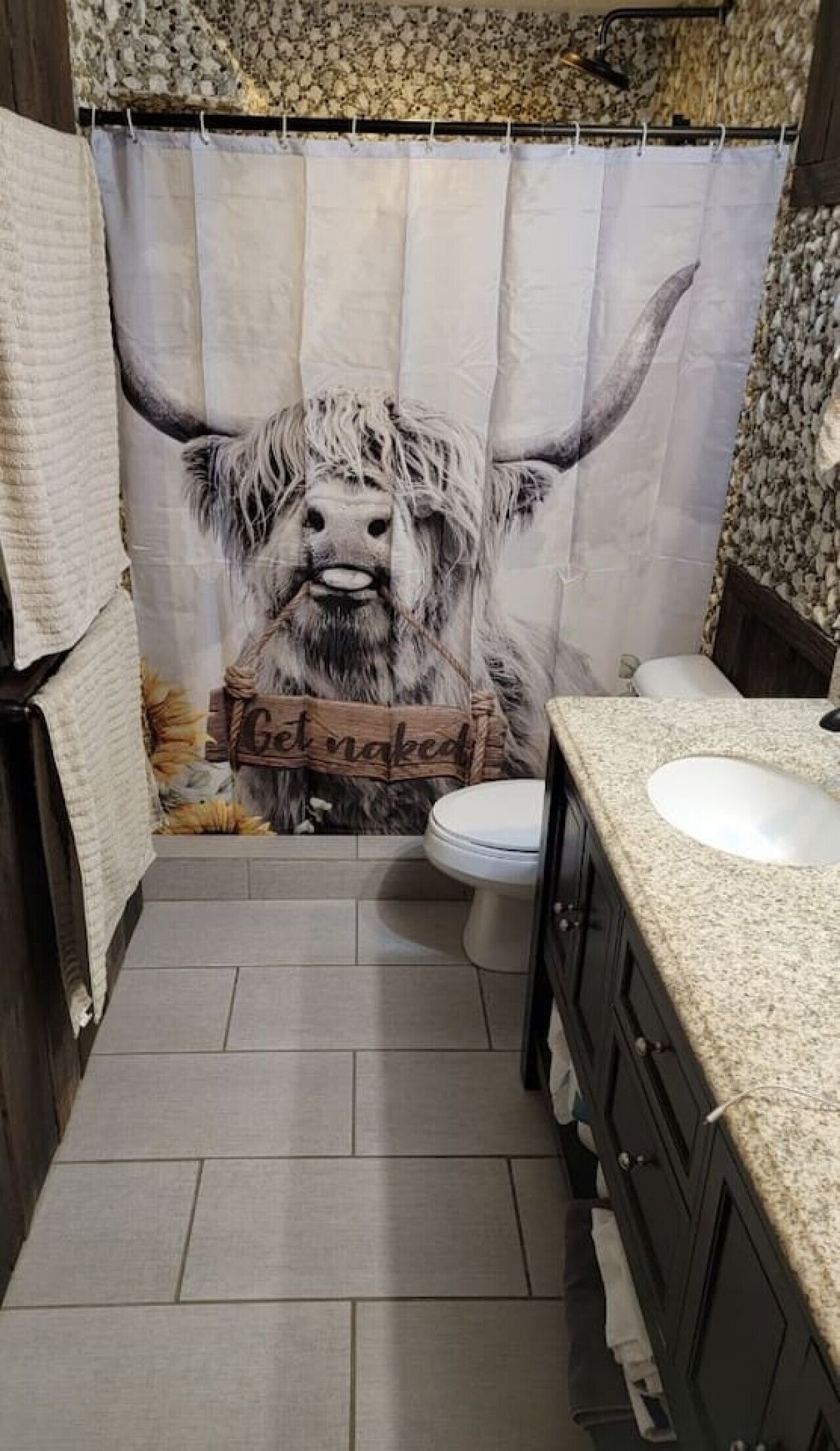 Une salle de bain avec un rideau de douche orné d’une tête de taureau et de l’inscription « Déshabillez-vous ».