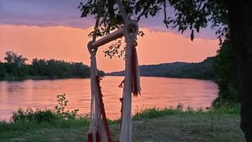 Una hamaca colgada de un árbol junto a un lago al atardecer.