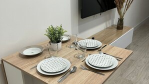 Une table à manger dressée avec des assiettes, des couverts et des verres, et un téléviseur fixé au mur au-dessus.