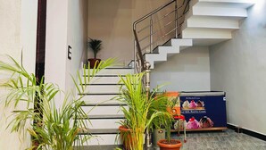A modern hotel lobby with a staircase, potted plants, and a reception desk. - Hotel Shridhar (Ujjain)