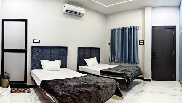A hotel room with two beds, a wardrobe, an air conditioning unit, and a curtain. - Hotel Shridhar (Ujjain)
