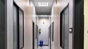 A long, narrow hallway with a reflective floor, flanked by doors with frosted glass panels. - Hotel Shridhar (Ujjain)