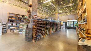 Een wijnkelder met wijnflessen op planken, een bar en een koelvitrine.