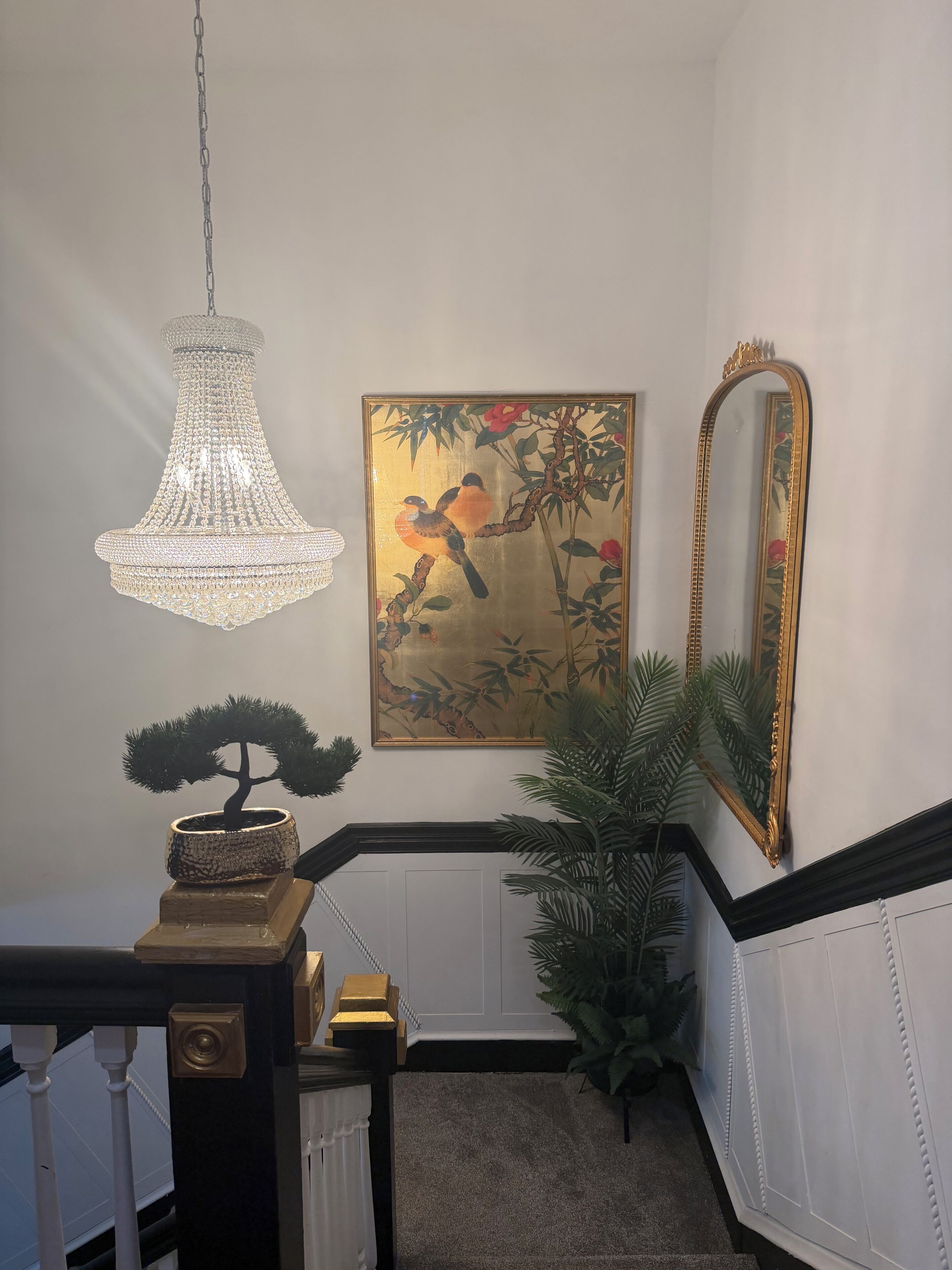 Un candelabro, un cuadro enmarcado, un espejo, un bonsái y una escalera.