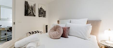 Habitación de hotel con una cama grande, una mesita de noche con lámpara y dos cuadros en la pared.