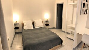 A neatly arranged bedroom with a bed, two bedside tables with lamps, a wardrobe, and a chair.