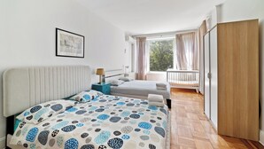 A bedroom with a bed, a bedside table, a lamp, a window with curtains, and a view of the outdoors. - Spacious 5-bedroom house in enjoyable Brooklyn (Brooklyn)