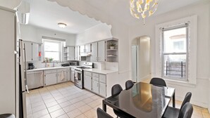 A modern kitchen with white cabinetry, a dining table with chairs, and a large window with a view. - Spacious 5-bedroom house in enjoyable Brooklyn (Brooklyn)