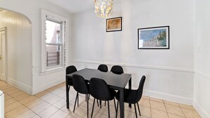 A dining area with a rectangular table and six chairs, a chandelier, and two framed pictures on the wall. - Spacious 5-bedroom house in enjoyable Brooklyn (Brooklyn)