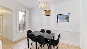 Un coin repas comprenant une table rectangulaire et six chaises, un lustre et deux tableaux encadrés accrochés au mur.