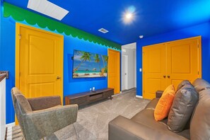 A room with blue walls, yellow doors, a TV on the wall, and a brown sofa.