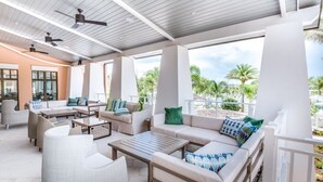 An outdoor lounge area with multiple seating options, ceiling fans, and large windows offering views of palm trees and the sky. - HOGARTS & AVATAR! MARIO Kart! Pool with Waterpark Close to Disney! (Kissimmee)