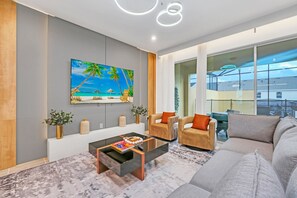 Una sala de estar moderna con un televisor grande, asientos cómodos, una mesa de centro y vistas al exterior.