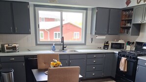 Una cocina moderna con armarios oscuros, una mesa de comedor con sillas, un ventanal con vistas y un microondas.