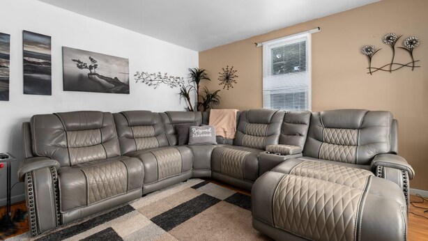 Un sofá modular en una sala de estar con pared beige, una ventana con persianas y decoración en la pared.