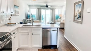 A modern kitchen with white cabinetry, a built-in dishwasher, and a large island.