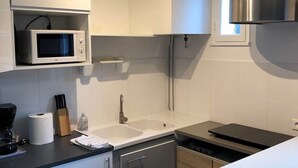Una cocina moderna con armarios blancos, microondas, fregadero y lavavajillas.