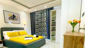 Ein modernes Hotelzimmer mit einem großen Bett, einem Holztisch und einem Kleiderschrank.