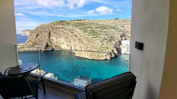 Ein Balkon mit freiem Blick auf eine zerklüftete Küstenlinie und das türkisfarbene Meer.