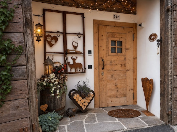 A rustic wooden door with a number plaque, a decorative heart-shaped planter, and a small animal figurine on the doorstep.