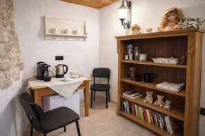 Una habitación acogedora con un escritorio de madera, dos sillas, una estantería y una cafetera.