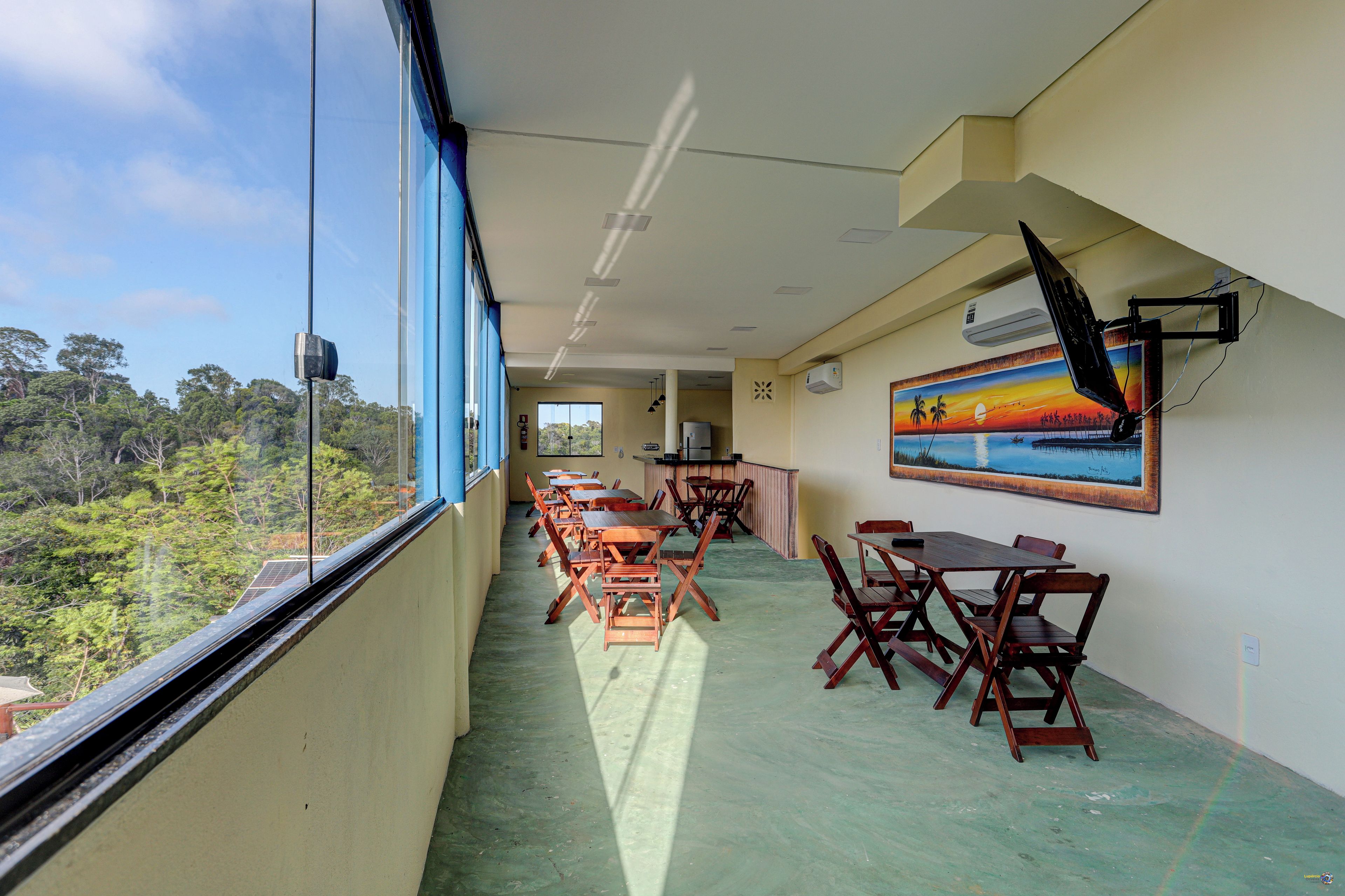 Un comedor con mesas y sillas, un cuadro en la pared y vistas al exterior.