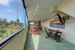 A dining area with tables and chairs, a painting on the wall, and a view of the outdoors. - Recanto Fiel (Itacaré)