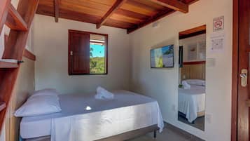 Un dormitorio con cama, techo de madera, ventana, espejo y puerta.