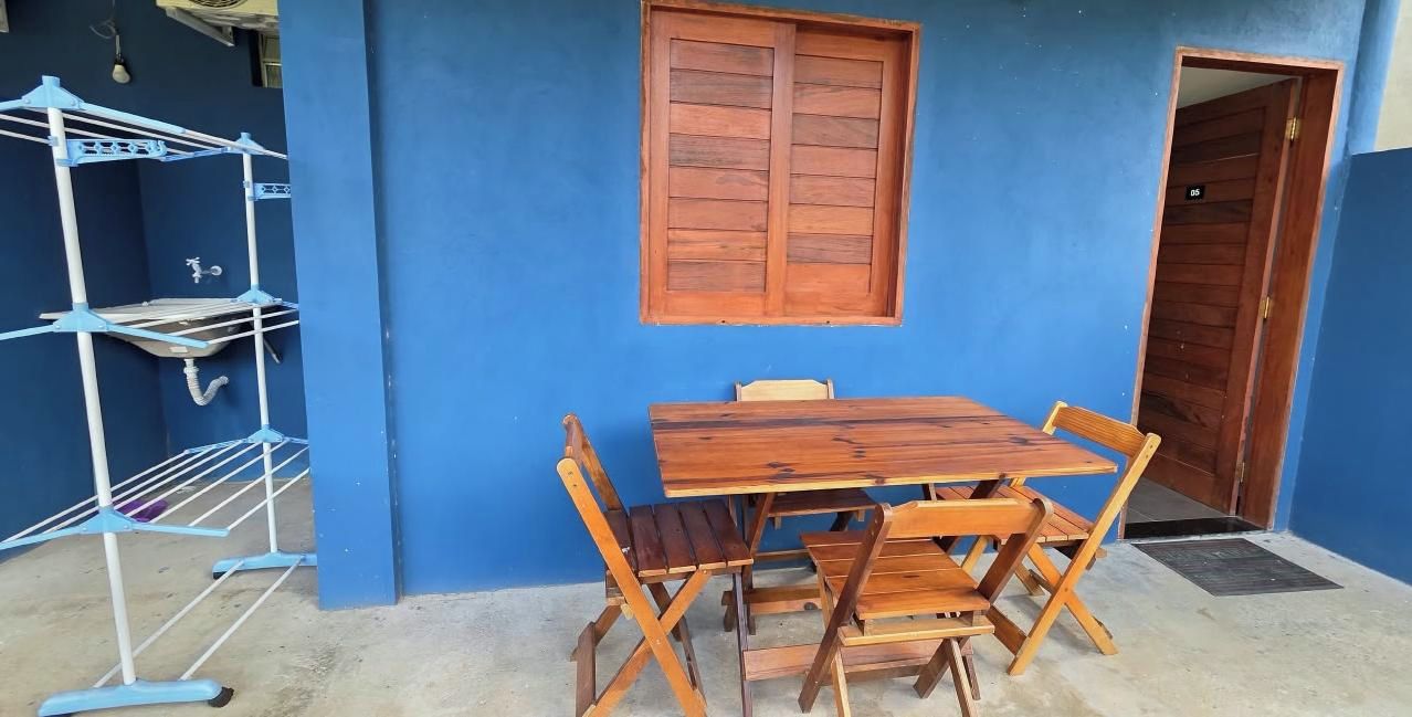 Eine blaue Außenwand mit einer Holztür, einem Fenster und einem Tisch mit Stühlen.