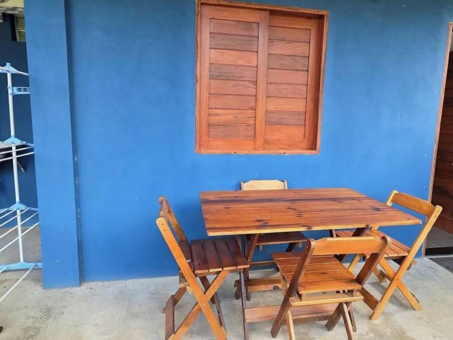 Eine blaue Außenwand mit einer Holztür, einem Fenster und einem Tisch mit Stühlen.