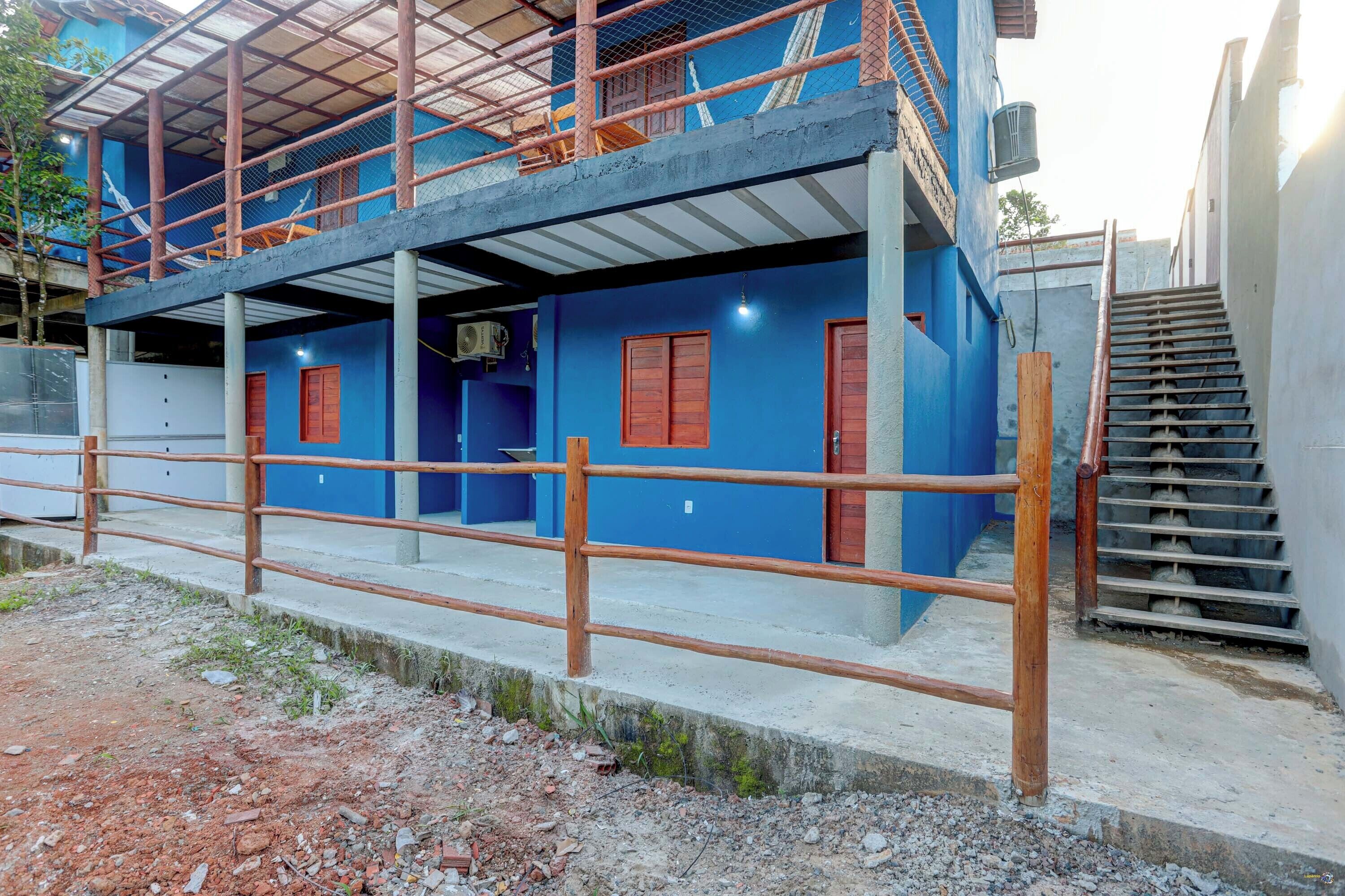 A two-story building with a blue exterior, a wooden staircase, and a metal railing.