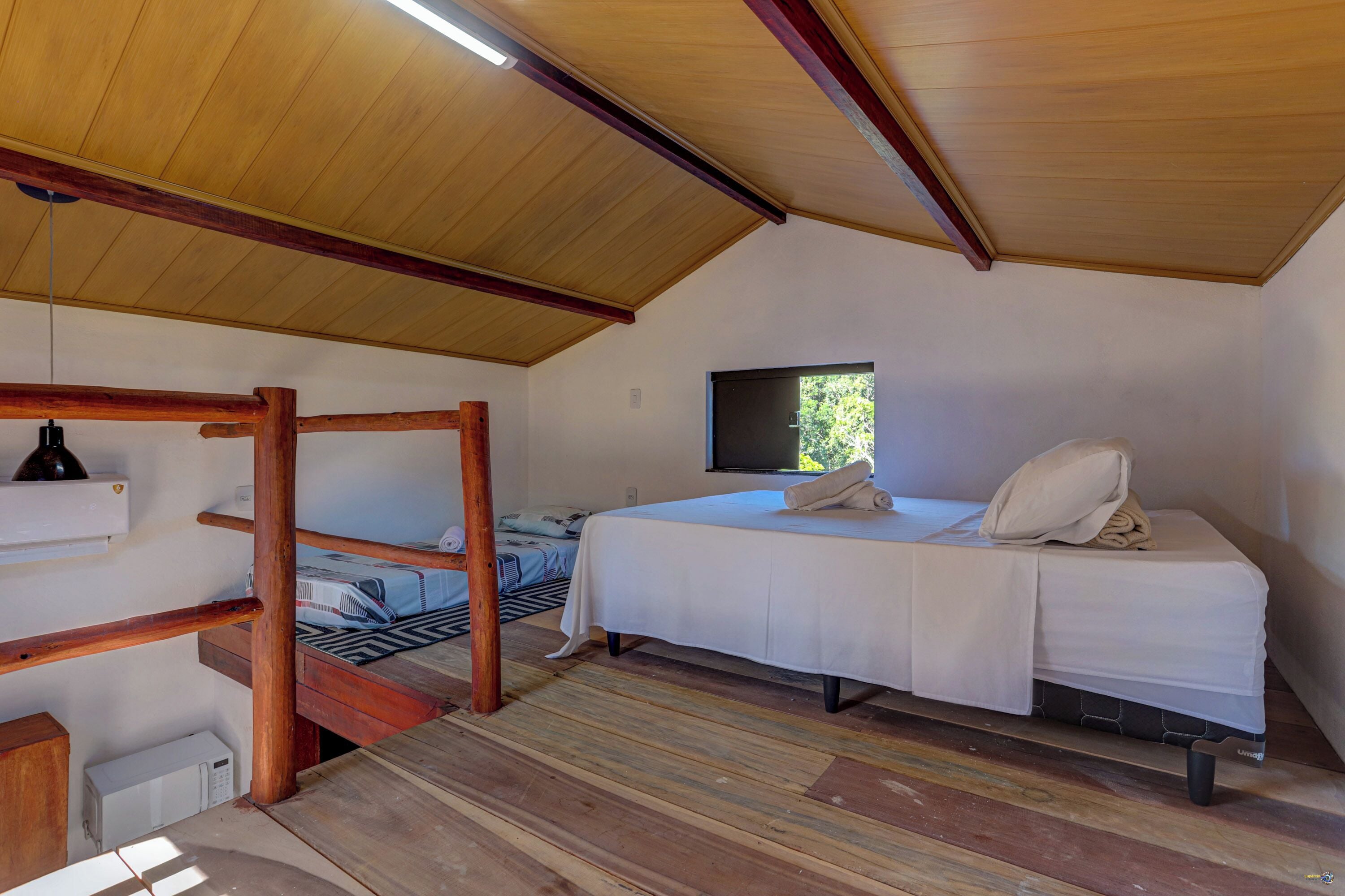 Una habitación compacta con literas, una cama individual, un televisor y una ventana pequeña.