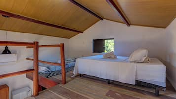 Una habitación compacta con literas, una cama individual, un televisor y una ventana pequeña.