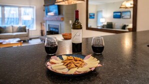 A dining area with a plate of food, two glasses of red wine, and a bottle of wine on a dark countertop. - 3BR/2BA, Ski in/out from A/B lift, pool & hot tub (Ludlow)