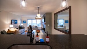 A modern kitchen with a central island, a dining area with a bowl, and a living room with a sofa and a TV. - 3BR/2BA, Ski in/out from A/B lift, pool & hot tub (Ludlow)