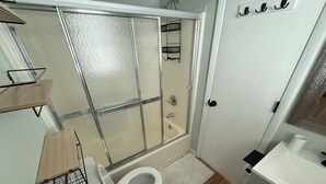 Une salle de bain avec une douche à parois de verre, des toilettes, un lavabo et un miroir.