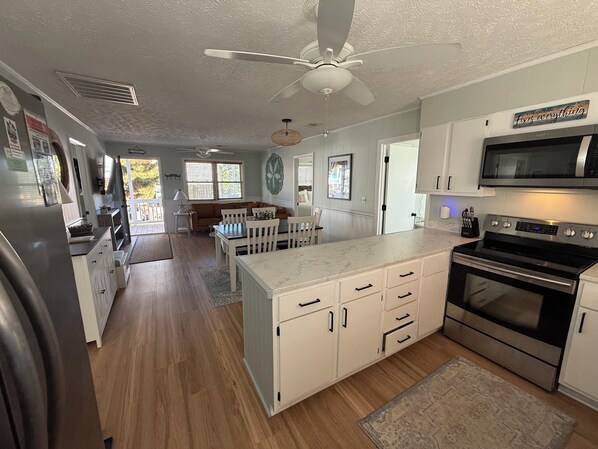A modern kitchen with white cabinetry, a large island, and a built-in oven. - Charming and cozy house in Sunset Beach and only a 5 min walk to the beach! (Sunset Beach)
