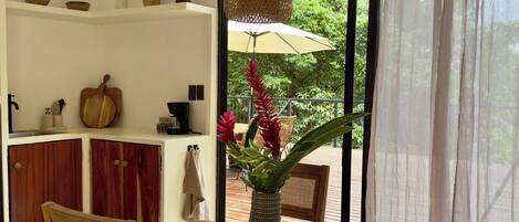 A dining area with a wooden table and chairs, a vase with flowers, and hanging woven light fixtures.