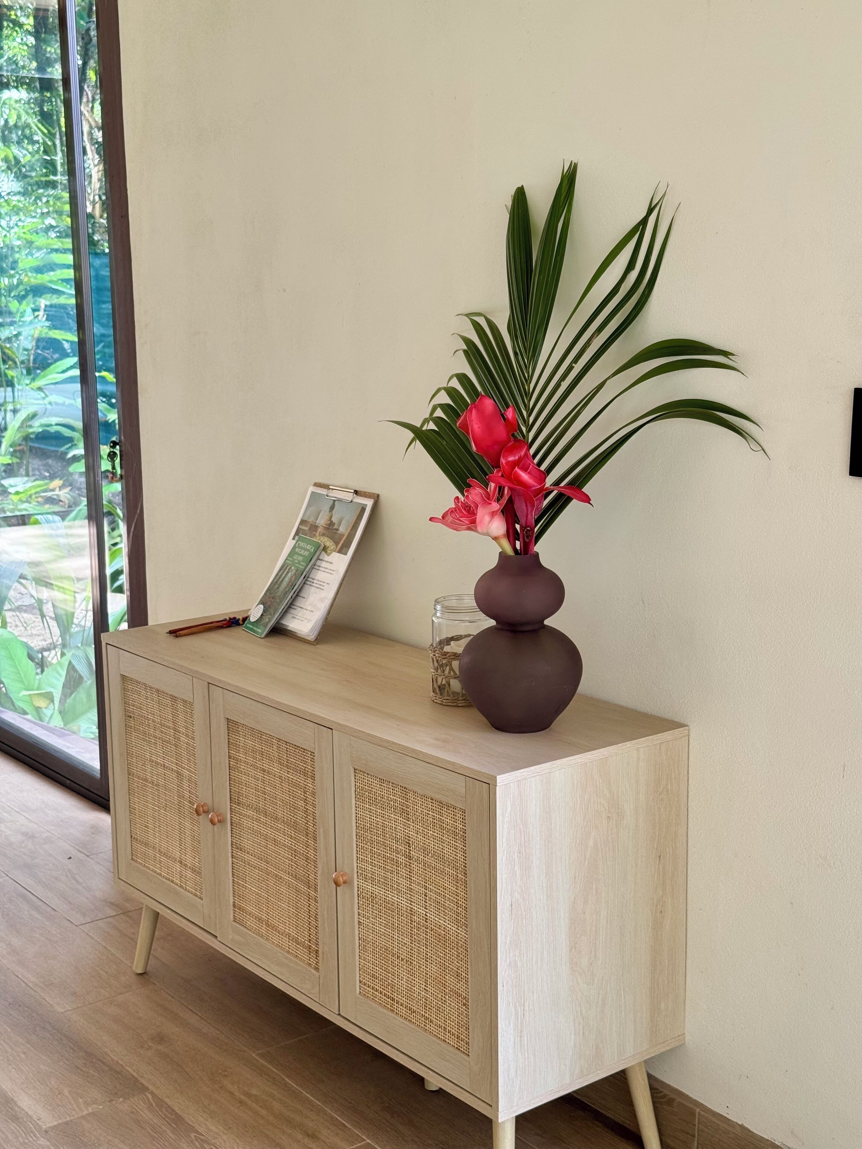 Un mueble de madera con un jarrón de flores y un cuadro encolado encima.