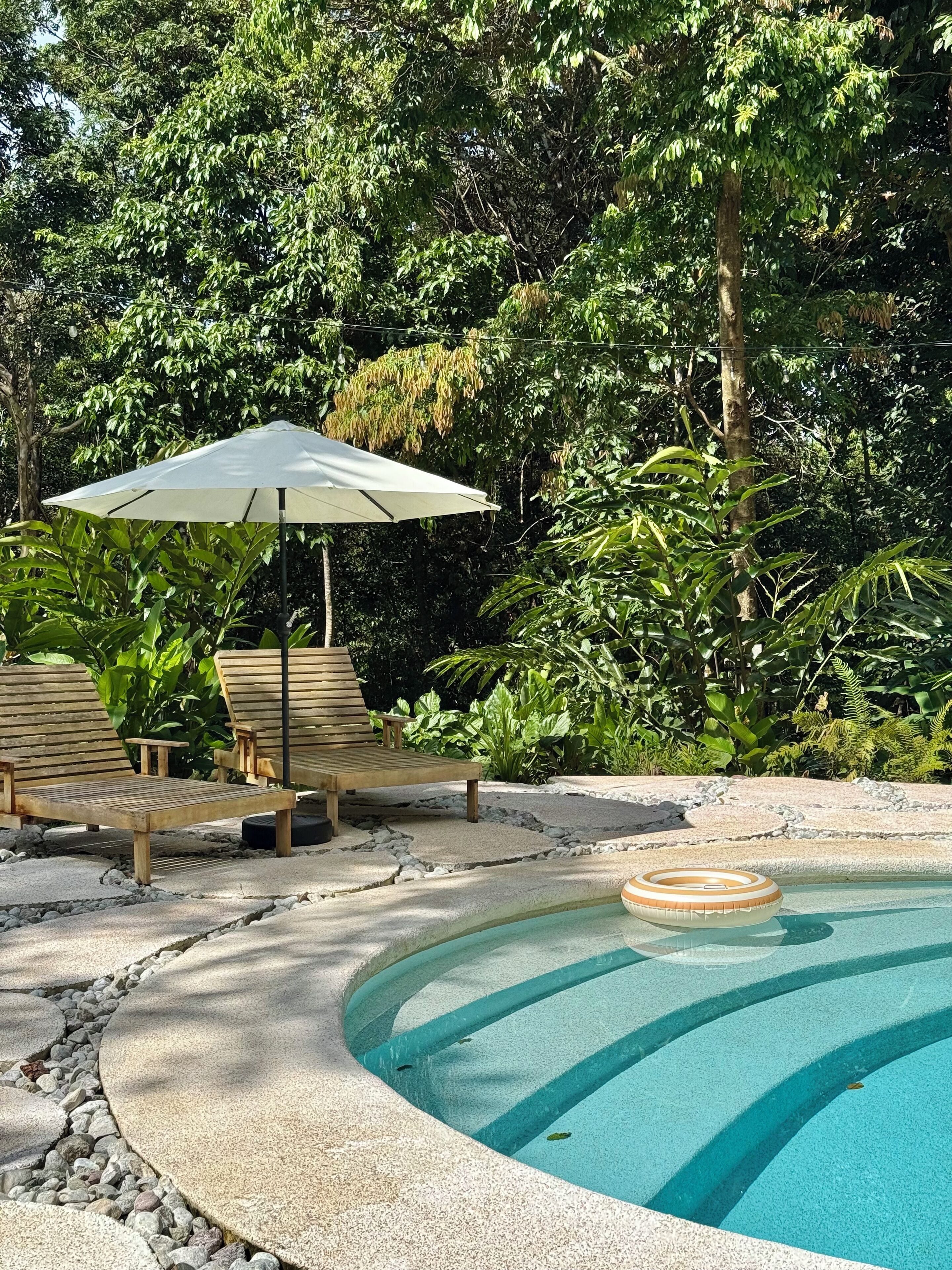 A pool area with lounge chairs and a sun umbrella.