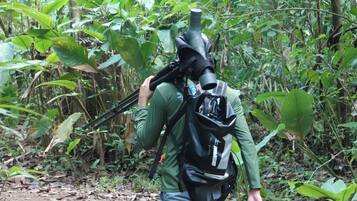 Una persona caminando por un bosque con una mochila y una cámara.