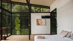 Une chambre avec une grande fenêtre, un lit et un climatiseur fixé au mur.