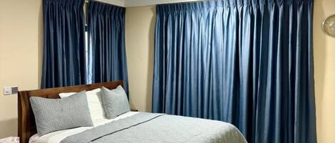 A bedroom with a wooden bed, a nightstand, a wall clock, and a ceiling fan.