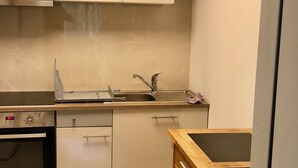 A modern kitchen with white cabinets, a stainless steel sink, and a built-in oven. - Apartment Deluxe (Rapperswil-Jona)