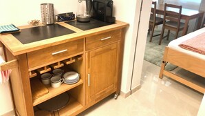A compact kitchenette with a coffee maker, kettle, and storage drawers. - Apartment Deluxe (Rapperswil-Jona)