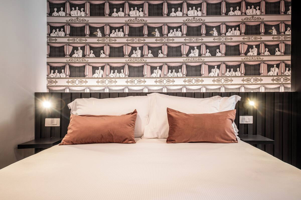 Ein Hotelzimmer mit einem großen Bett, zwei Nachttischen und einer Wand mit einem gemusterten Design.