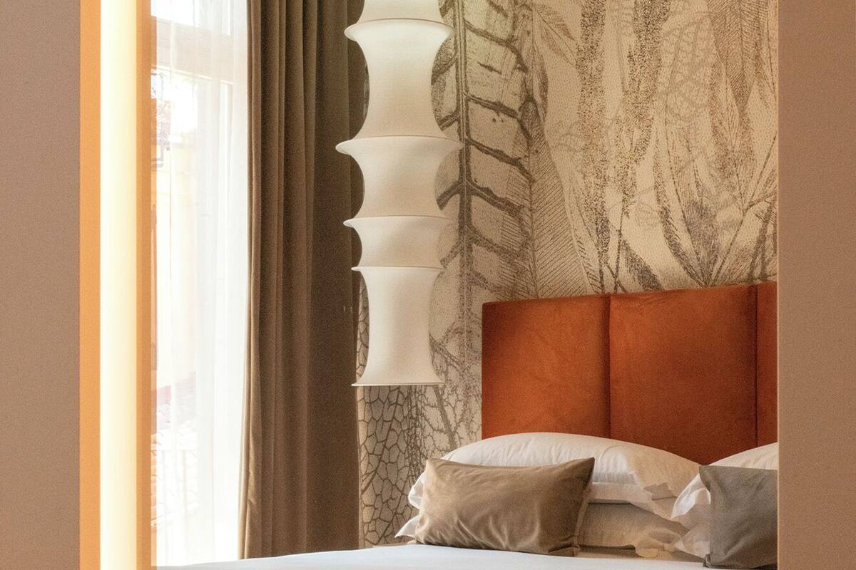 Ein Hotelzimmer mit einem Bett, einer großen Wandleuchte und einem Fenster mit Vorhängen.