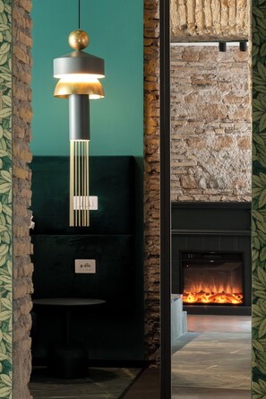A modern interior with a fireplace, a hanging light fixture, and a green wall. - Colonna Collection (Rome)